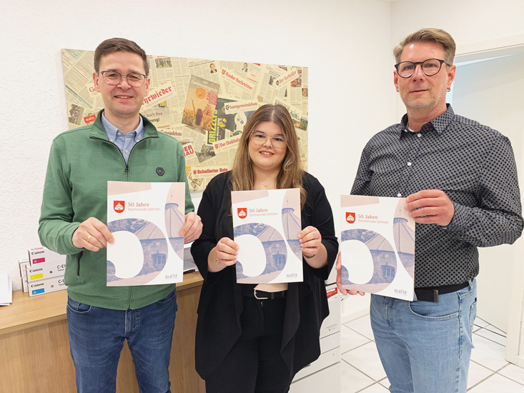 Oliver Kroll und Daria-Sue Grabarek vom Gleitz Verlag präsentieren gemeinsam mit Bürgermeister René Marienfeldt die Broschüre zum 50. Geburtstag der Gemeinde Söhlde.