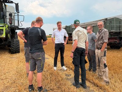 Christopher Gedeon mit den Landwirten auf dem abgeernteten Weizenfeld